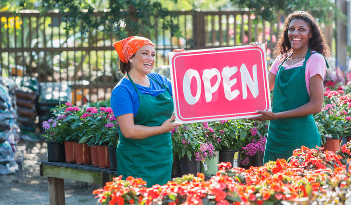Deux femmes tenant un panneau « Business open »