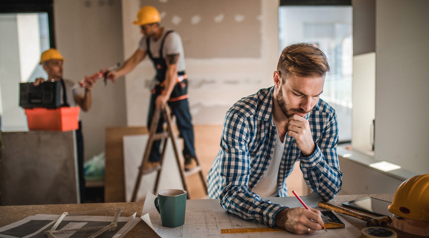 Un homme planifie la construction avec des ouvriers en arrière-plan